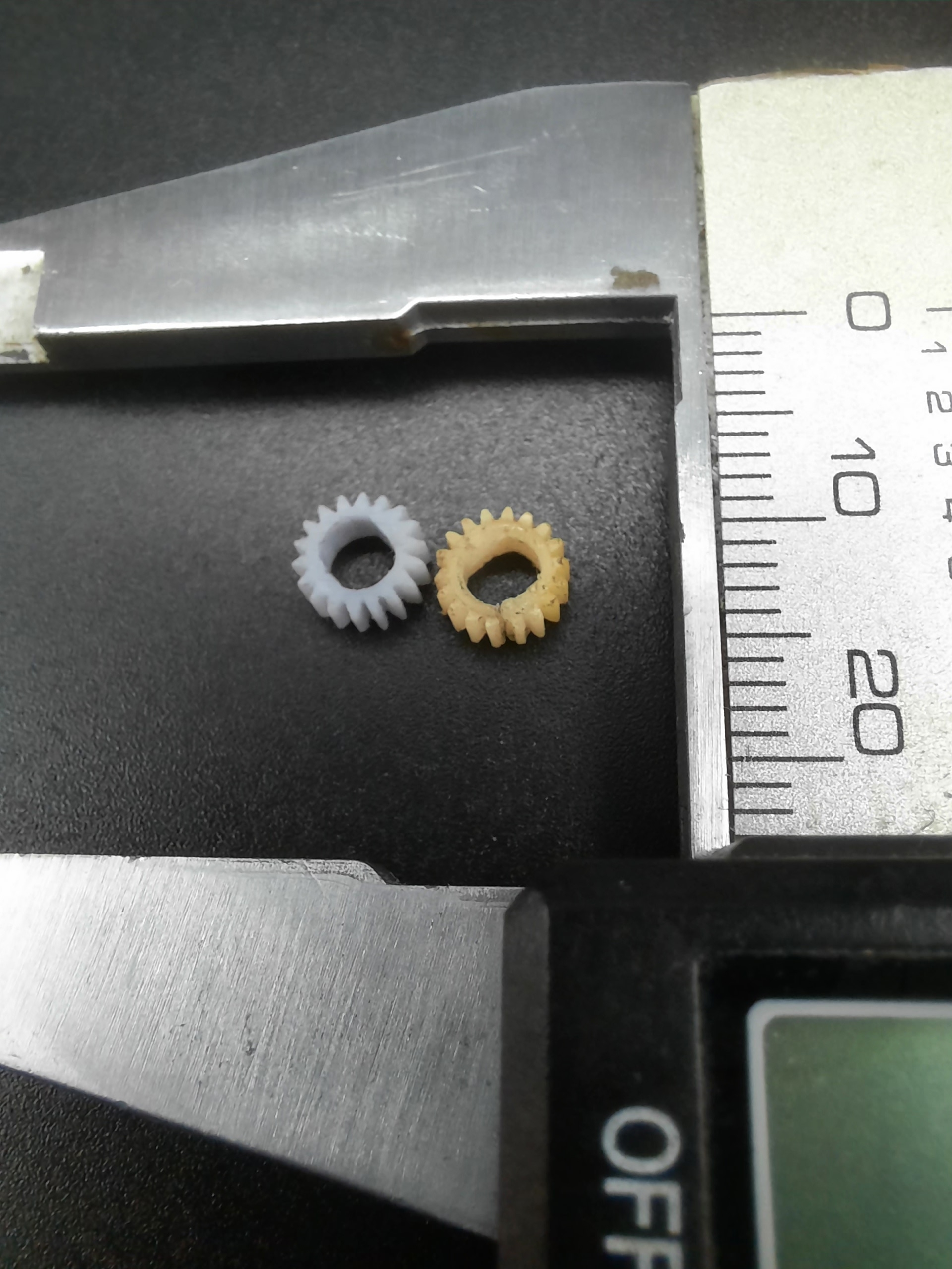 Воссозданная миниатюрная шестерня рядом с оригиналом и измерительным инструментом